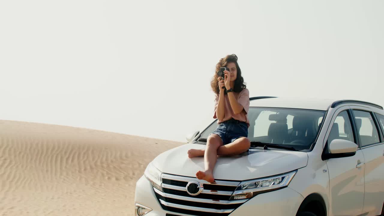 mujer fotografiando en el desierto en un coche