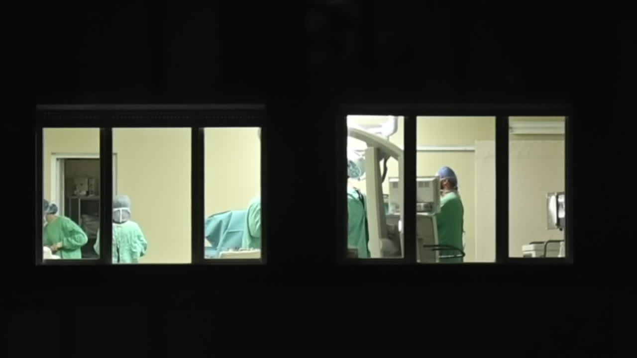 Window view of doctors during an operation at night