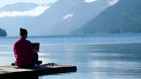woman working on laptop by a lake