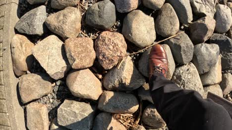 taking mindful steps over loose stones, enjoying the sunshine in brown shoes.