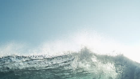 slow motion wave rolling across open ocean with soft foam and sky above