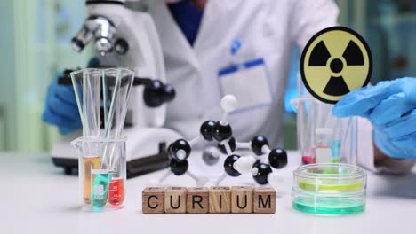 a laboratory setting with scientific equipment, molecular model, beakers, and a curium sign with a scientist in the background