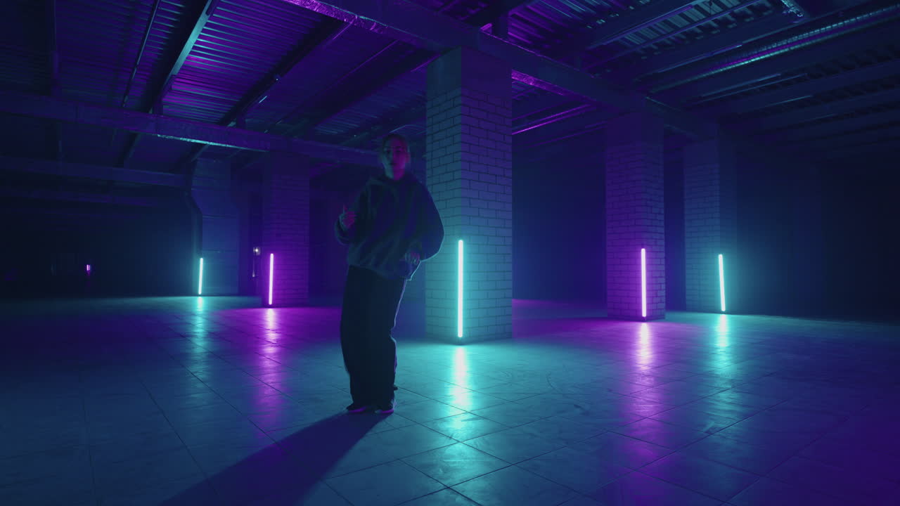 bailarina elegante se mueve a la música en una habitación llena de humo con iluminación de neón. mujer dando una actuación en solitario en estilo hip hop en la escena del club con lámparas de neón de fondo