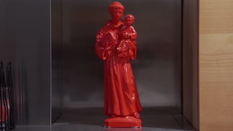 red statuette of a saint holding a saint and a book