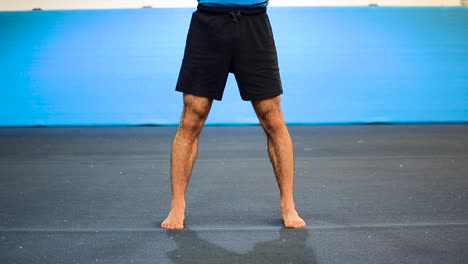 a still shot of a guy doing squats in a gymnastics gym