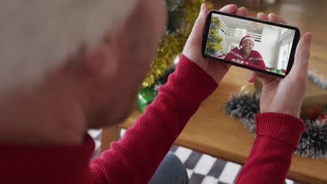 Hombre-Caucásico-Con-Sombrero-De-Santa-Usando-Un-Teléfono-Inteligente-Para-Una-Videollamada-Navideña-Con-Una-Mujer-Sonriente-En-La-Pantalla