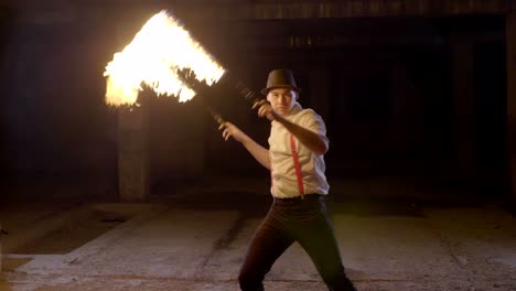 artista masculino realizando un espectáculo de fuego en la oscuridad en cámara lenta.