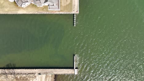 A-top-down-drone-view,-directly-above-the-shore-of-the-Great-Bay-in-Bay-Shore,-NY-on-a-sunny-day