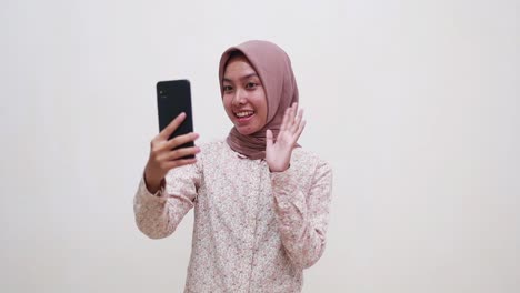 young asian muslim woman standing while video call on smartphone