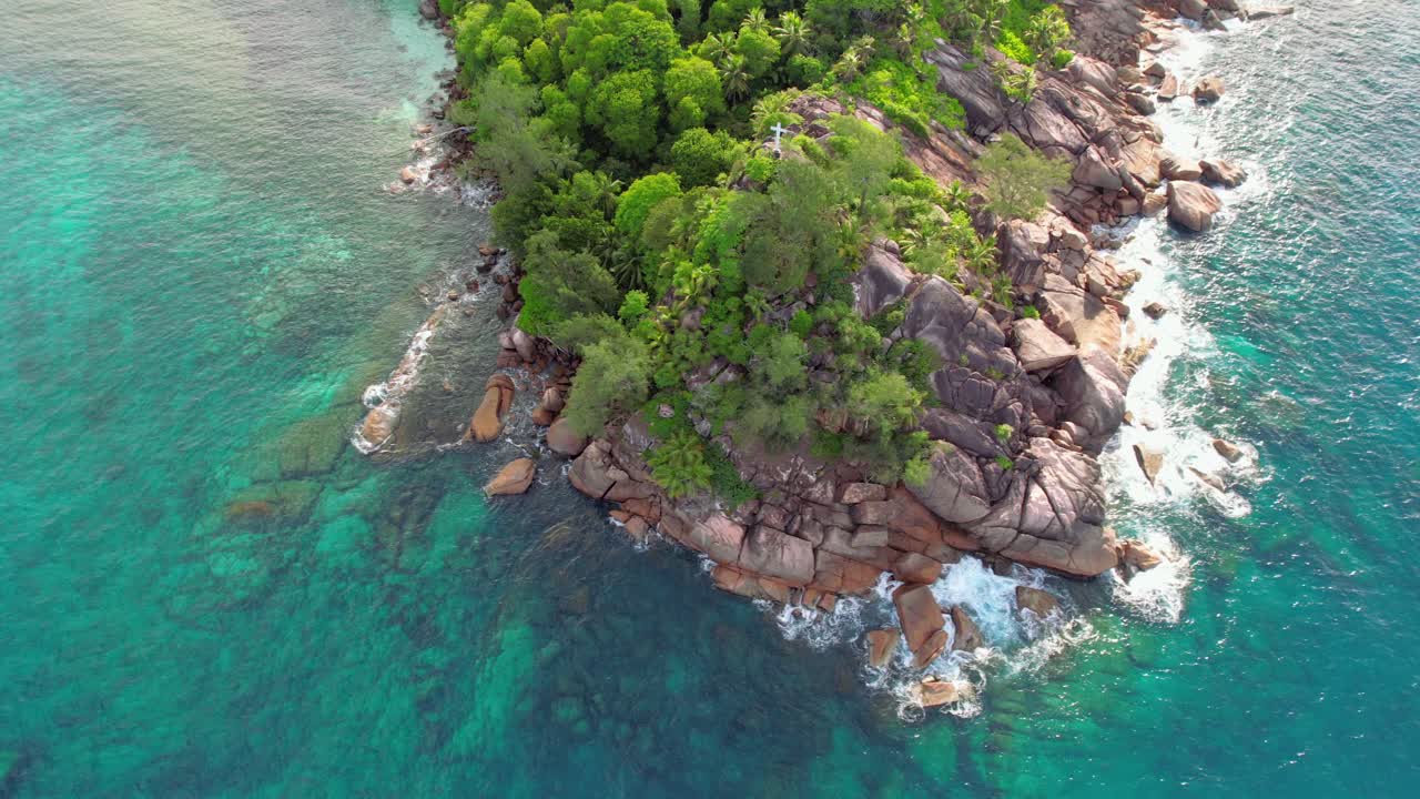 Ripresa drone di collina e rocce di granito, una croce bianca e acqua turchese alla spiaggia di Baie Lazare, Mahé Seychelles 30fps