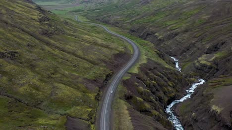 car driving on winding road in the mountains of iceland with drone video following