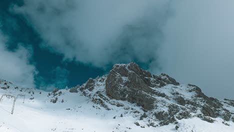 over the peak of engelberg, partly covered in snow, cloud formation is shot in a timelapse