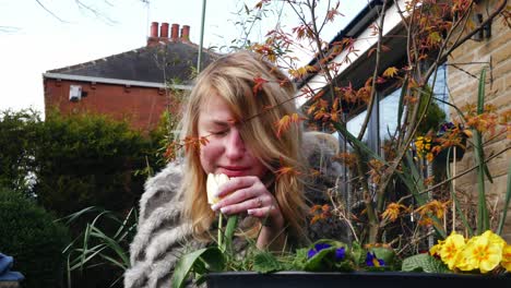 Attractive-woman-enjoying-enjoying-scent-of-flowers-in-garden-medium-zoom-in-shot-slow-motion-portrait