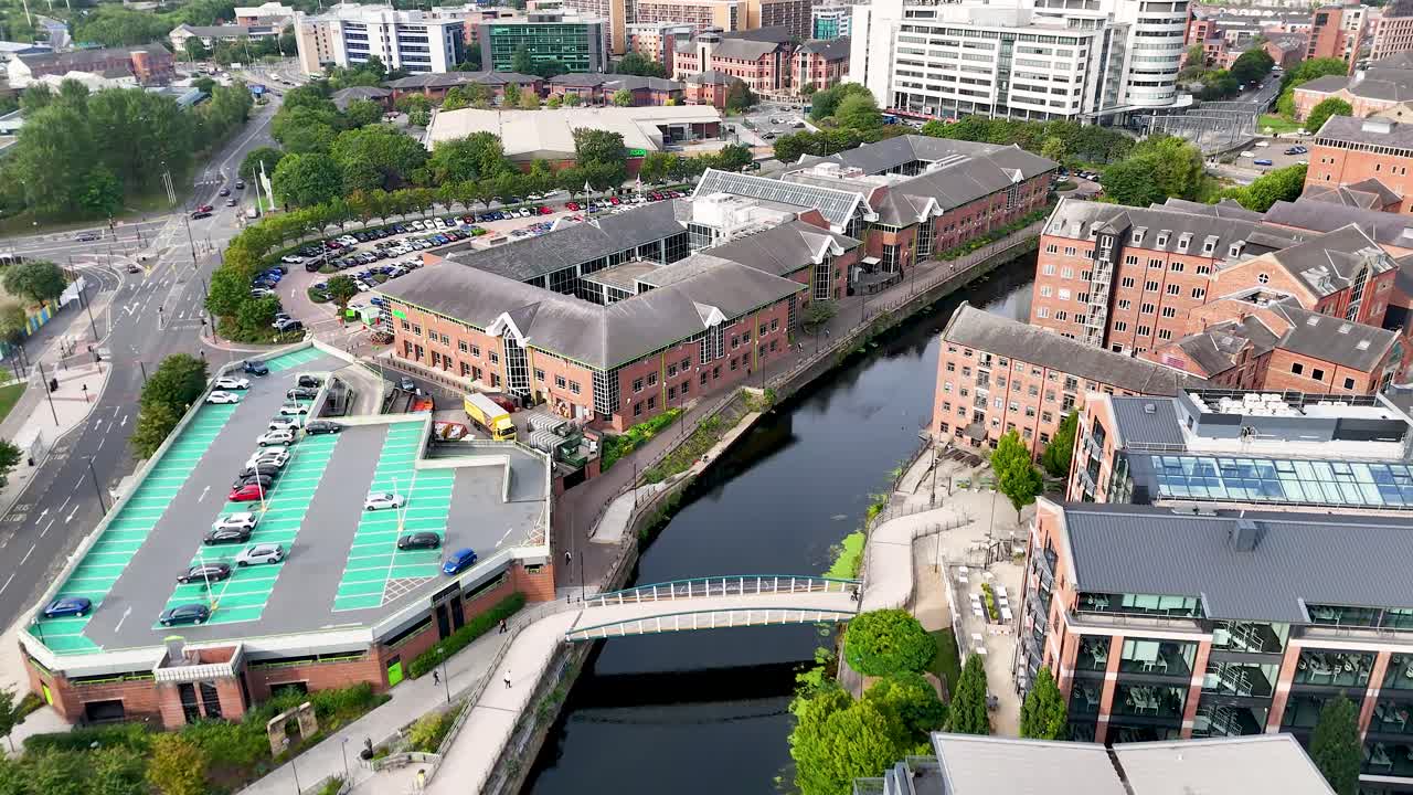 High-angle aerial footage smoothly pans above a Victorian-era cityscape with brick buildings, a river, bridges, and urban streets in bright daylight