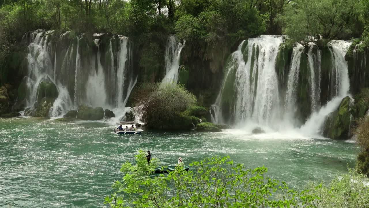 Turisti su barche a remi si avvicinano alle spettacolari cascate di Kravica in Bosnia