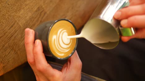 pouring latte art into a cup of coffee