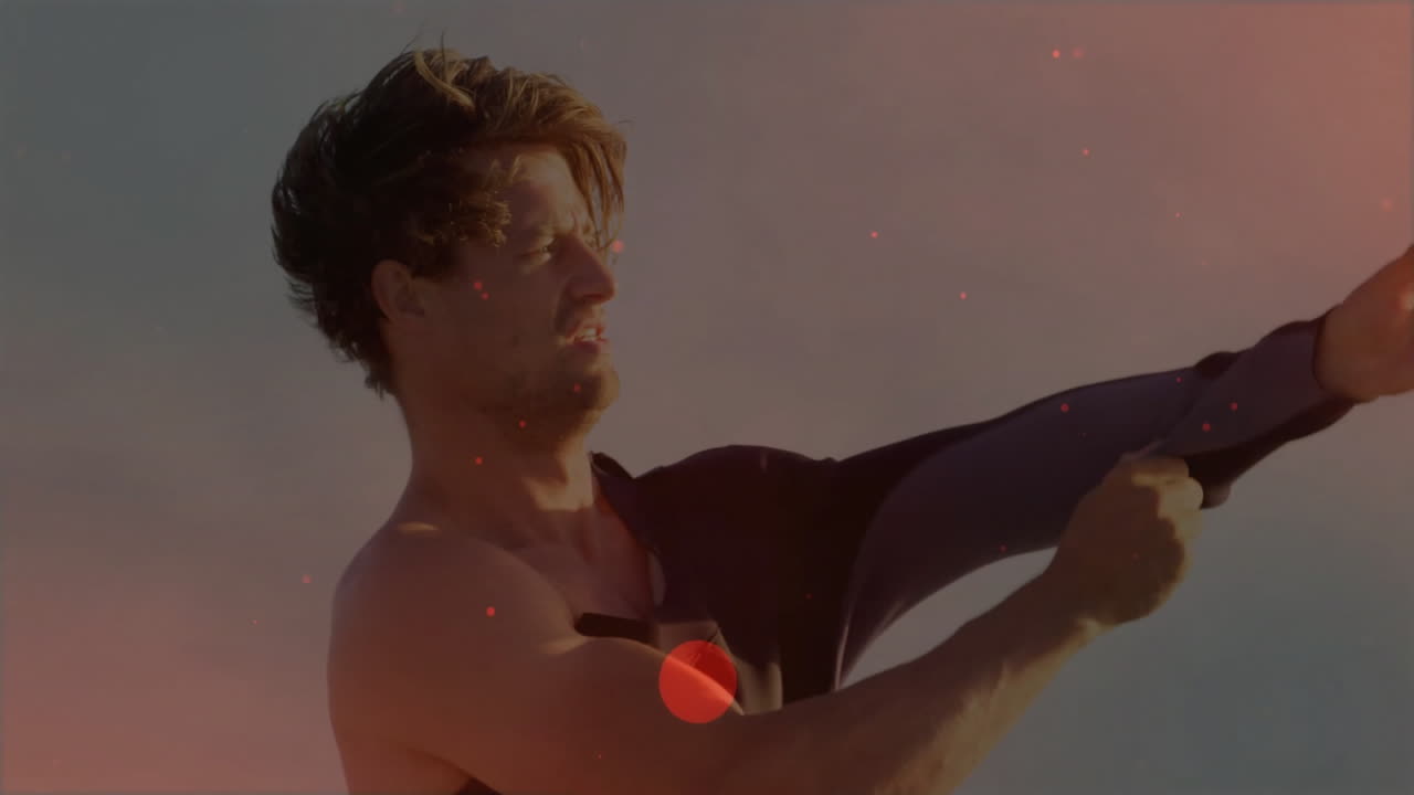 man pulling wetsuit on beach at sunset, with animated fitness graph and heart icon overlaying