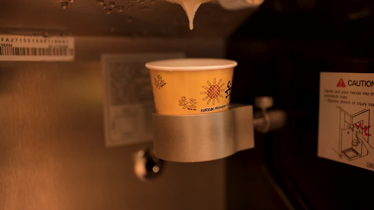 Nærbillede af en hånd, der sætter en kop ind i en automatisk drikkevareautomat.