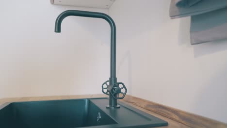 motion past black stylish faucet and sink at wooden counter