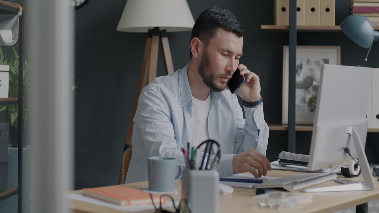 Mand arbejder ved computer og taler i telefon