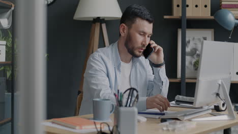 man working on computer and talking on phone