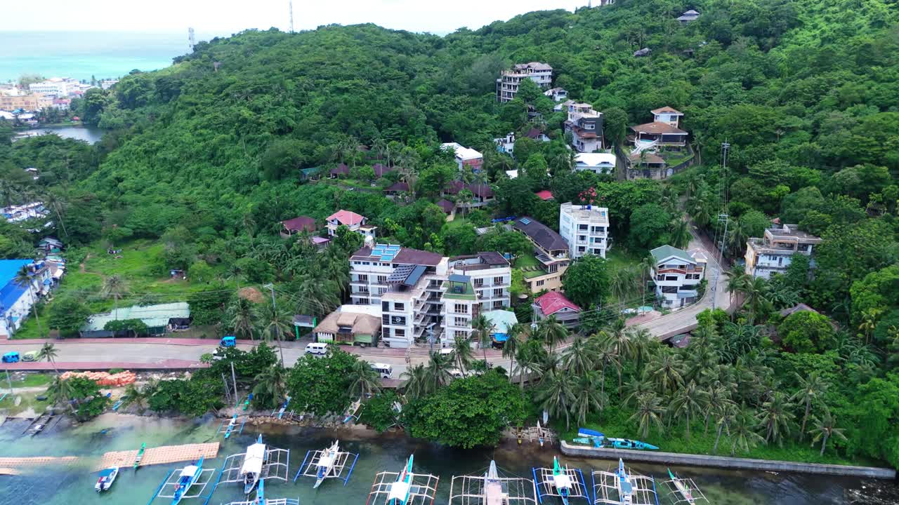 aerial of Boracay, Philippines showing fishing boats along a palm-lined shore, hillside villas, and turquoise waters. Perfect for travel, weather, and cinematic footage