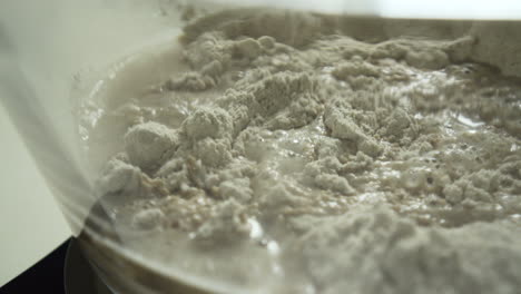 adding water to the flour and mixing with a plastic spatula