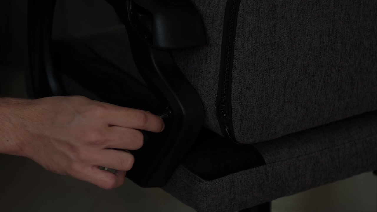 Bidikan close-up tangan yang menggunakan kunci L untuk menyetel dudukan kursi gaming saat perakitan furnitur dalam ruangan.