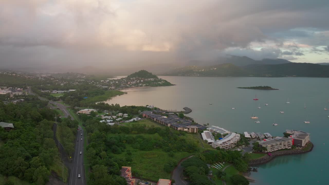 airlie beach bay lagoon coral sea marina drones aéreos carros de estrada em direção a cannonvale rosa amarelo nascer do sol manhã chuva coração da grande barreira de recife whitsundays whitehaven cais iates movimento para trás