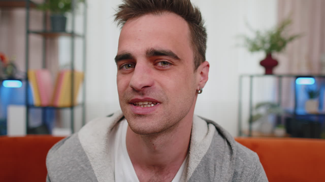 행복한 한 명의 잘생긴 십대 남자의 초상화 면도되지 않은 남자 소년은 소파에서 집에서 카메라를 보고 미소 짓고 있습니다.