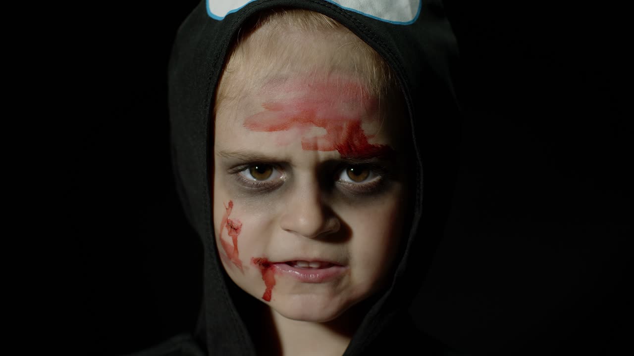 Halloween, angry girl with blood makeup on face. Kid dressed as scary skeleton, posing, making faces
