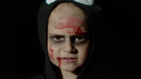 halloween, angry girl with blood makeup on face. kid dressed as scary skeleton, posing, making faces