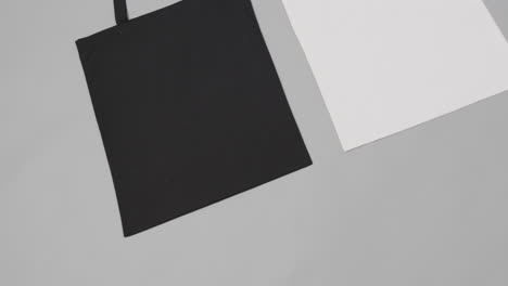 Close-up-of-white-and-black-bags-on-grey-background,-with-copy-space,-slow-motion