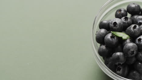 micro video of close up of bowl with blueberries with copy space on green background