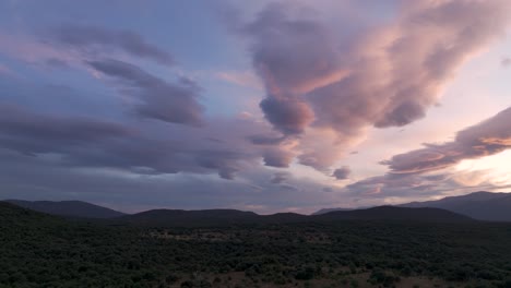 flight at sunset and with a turn of the camera we see a valley with its lush forests with a spectacular sky with elongated clouds that go from blue to orange, these mountains take on a dark blue tone