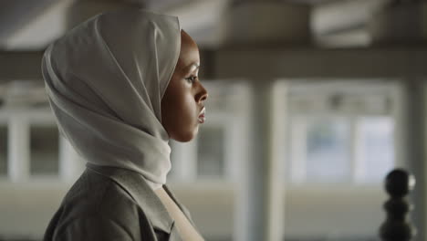 melancholic black woman with hijab walks along embankment