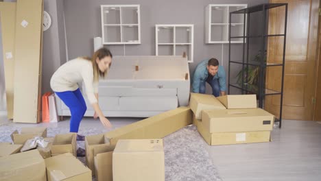 Husband and wife move sofa to new flat, then sit down and feel exhausted after hard work.