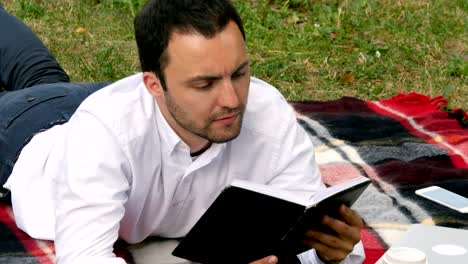 un joven empresario guapo leyendo un libro en el parque.