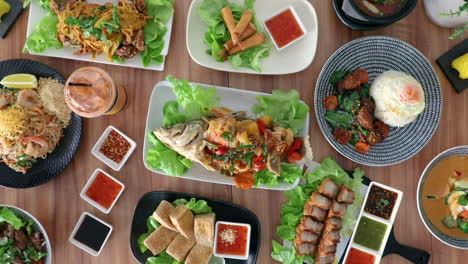 male hand placing thai cuisine spring roles onto flat lay food arrangement