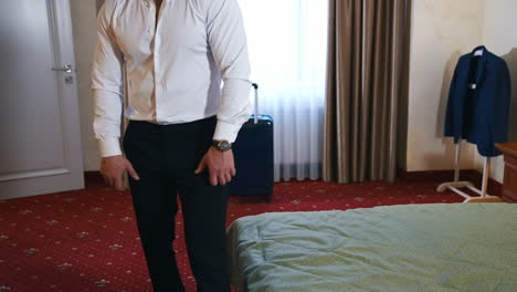 elegant man in comfortable hotel room. businessman tired after a long journey and resting on bed. handsome young traveler relaxing in hotel.