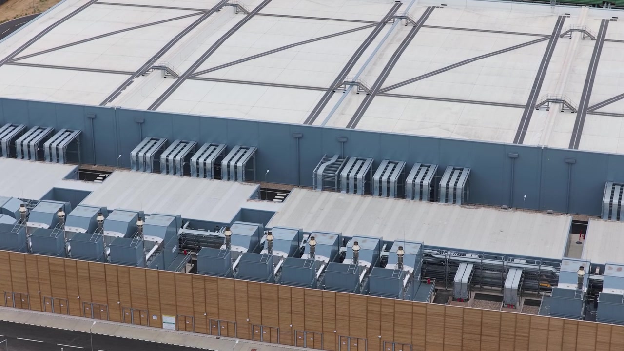 Industrial building housing server infrastructure and cooling systems seen from high altitude in a suburban area during the day