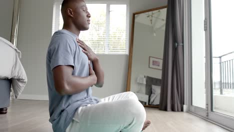 African-american-man-doing-yoga-and-meditating-at-home,-slow-motion