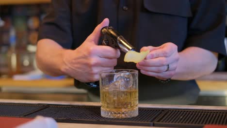 in this video, a skilled bartender showcases cocktail preparation. he lights a lemon slice, cuts a pineapple, and pours a drink over ice, highlighting his creativity and attention to detail