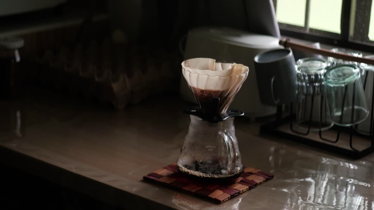 Brewed Coffee Dripping into Glass Carafe Through Pour-Over Filter Paper and V60 on Kitchen countertop - medium static shot