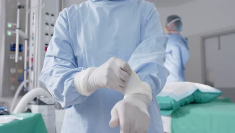 diverse male and female surgeons with face masks wearing medical gloves in slow motion, unaltered