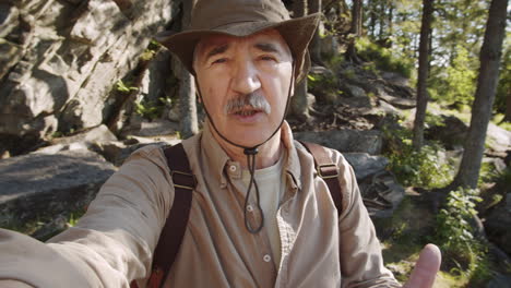 senior man hiking and taking a selfie in the forest