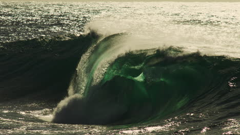 mid curl wave barrels with white mist illuminated by soft light over textured ocean surface
