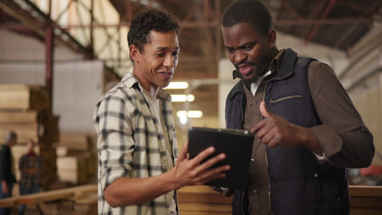 Two men in a warehouse looking at a tablet