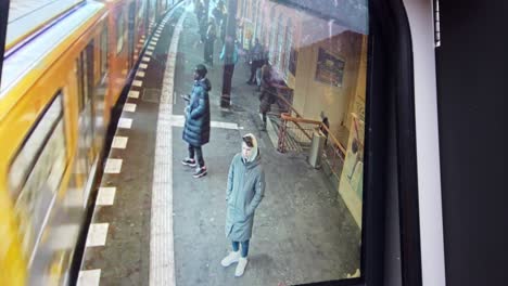 antiguo monitor en la estación de tren de berlín con gente esperando el metro