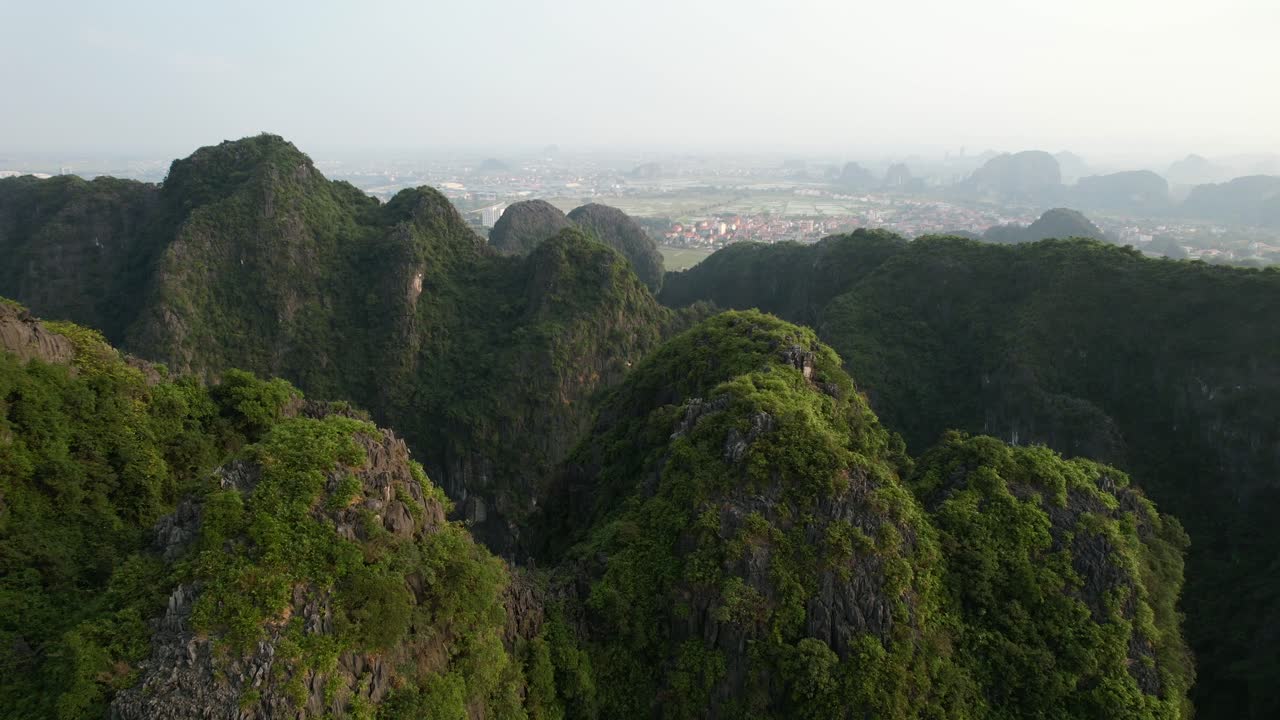drone volando sobre cumbres verdes de la cordillera de piedra caliza en la ciudad de tam coc en ninh binh vietnam al atardecer